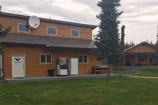 a house that has a clock at the top of a grass covered field