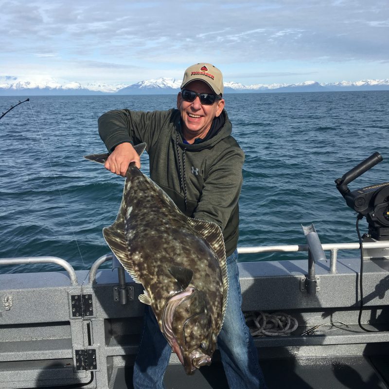 a man sitting on a bench next to a body of water