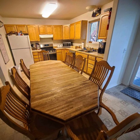 Kitchen with wooden dining table, chairs, and wooden cabinets.