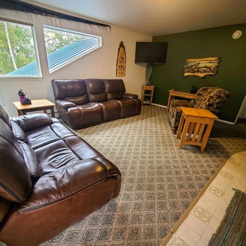 Cozy living room with brown leather sofas, green wall, and a wall-mounted TV.