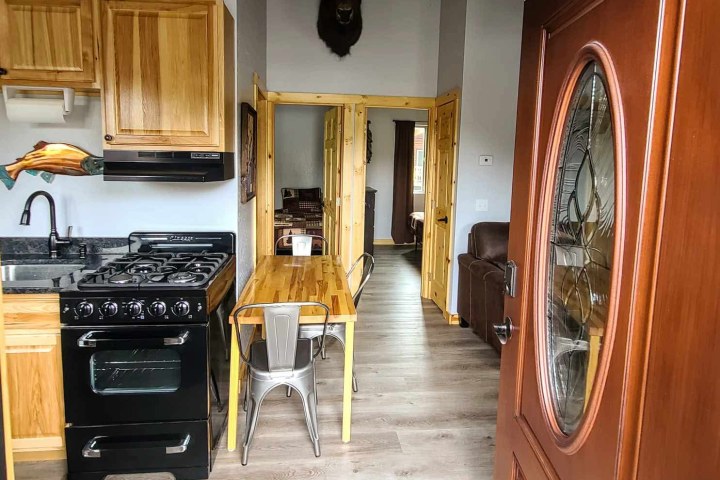View of a small kitchen with a wooden table and a buffalo head mounted on the wall.