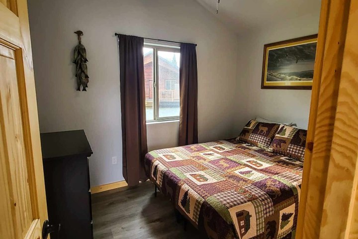 Cozy bedroom with quilt, ceiling fan, artwork, and window with curtains.