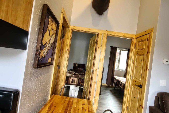 Room with wooden table and bison head mount above doorway, leading to bedrooms.
